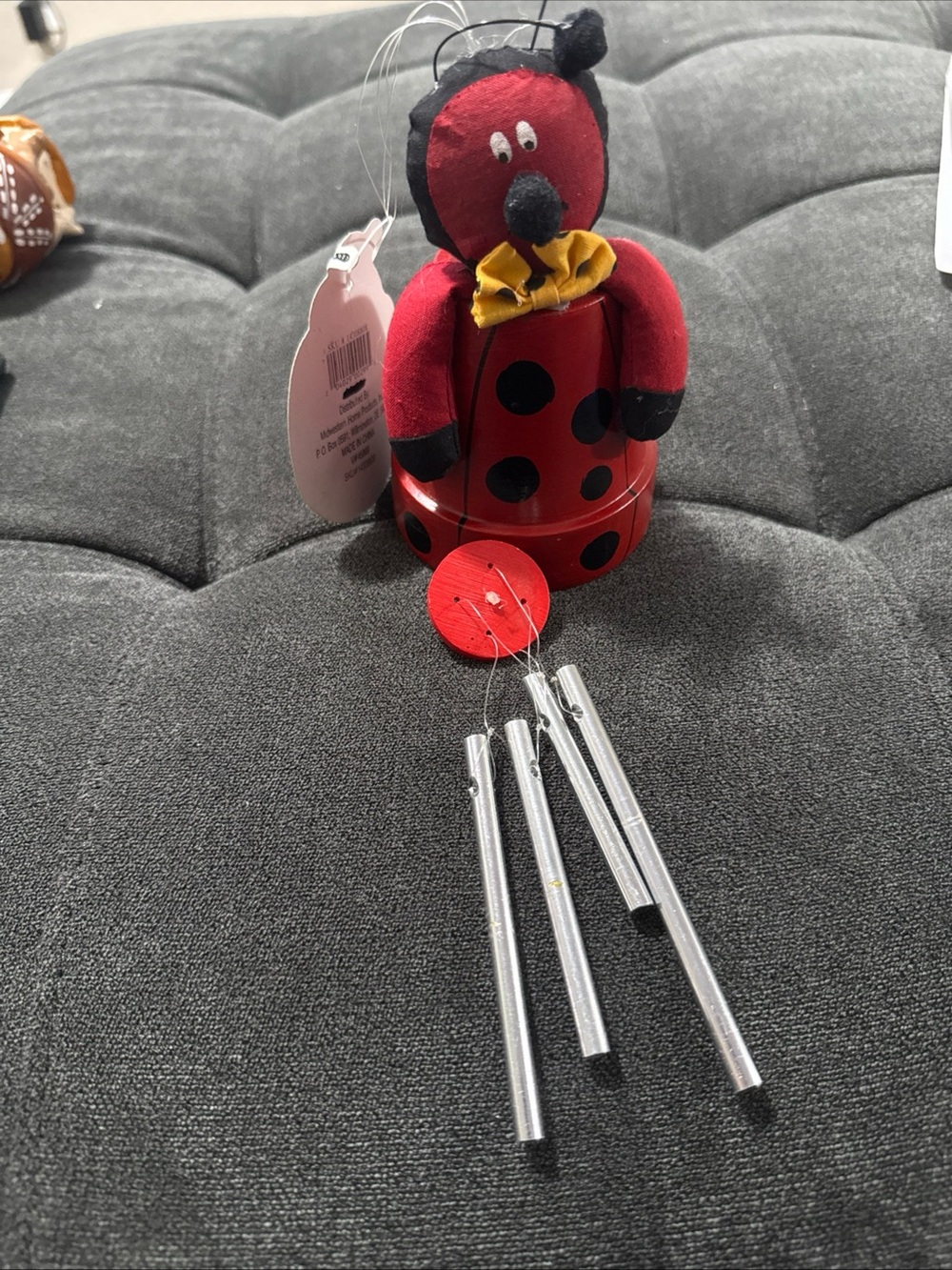 Red Ladybug Wind Chime Plush sitting on a pot colored red with black polka dots